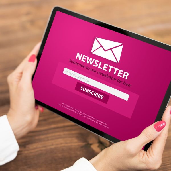  woman holding a tablet with a newsletter Signup Page on a screen.