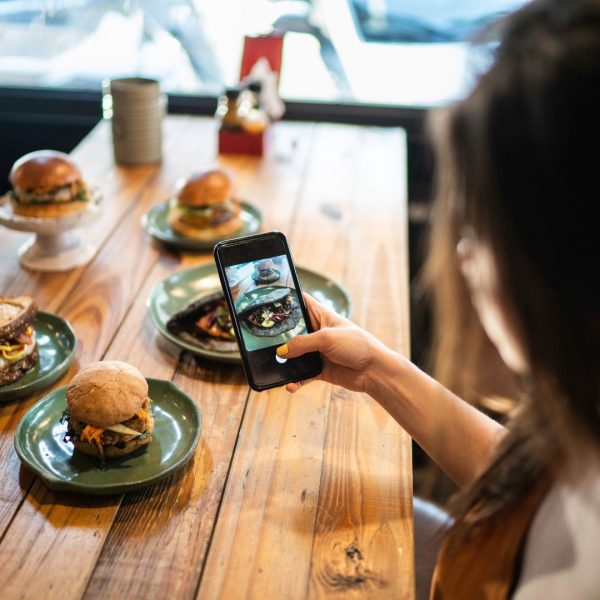 A food influencer filming hamburgers on a table.