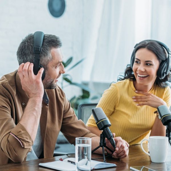 Two hosts recording a podcast in a recording studio.