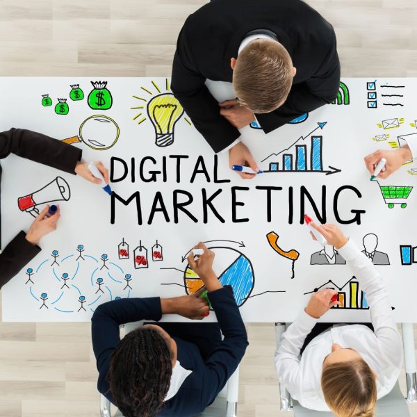 People in a digital marketing agency drawing a digital marketing diagram on a white table.