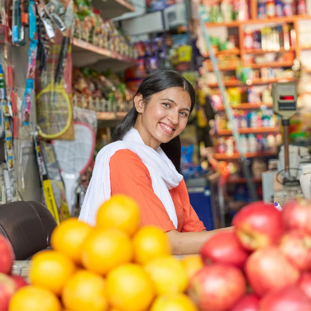 A small business owner in front of her shop near fruits, wondering if she should engage a local SEO marketing agency to improve her online presence and increase a store visits.